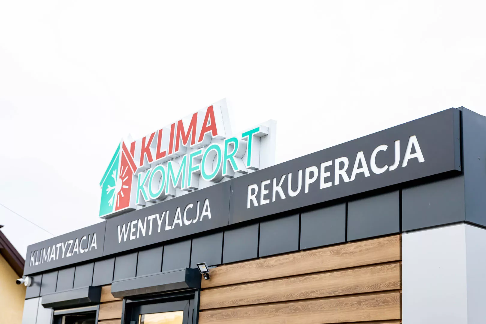 Fasada biura firmy Klima Komfort z dużym podświetlanym logo oraz napisami "KLIMATYZACJA", "WENTYLACJA" i "REKUPERACJA".